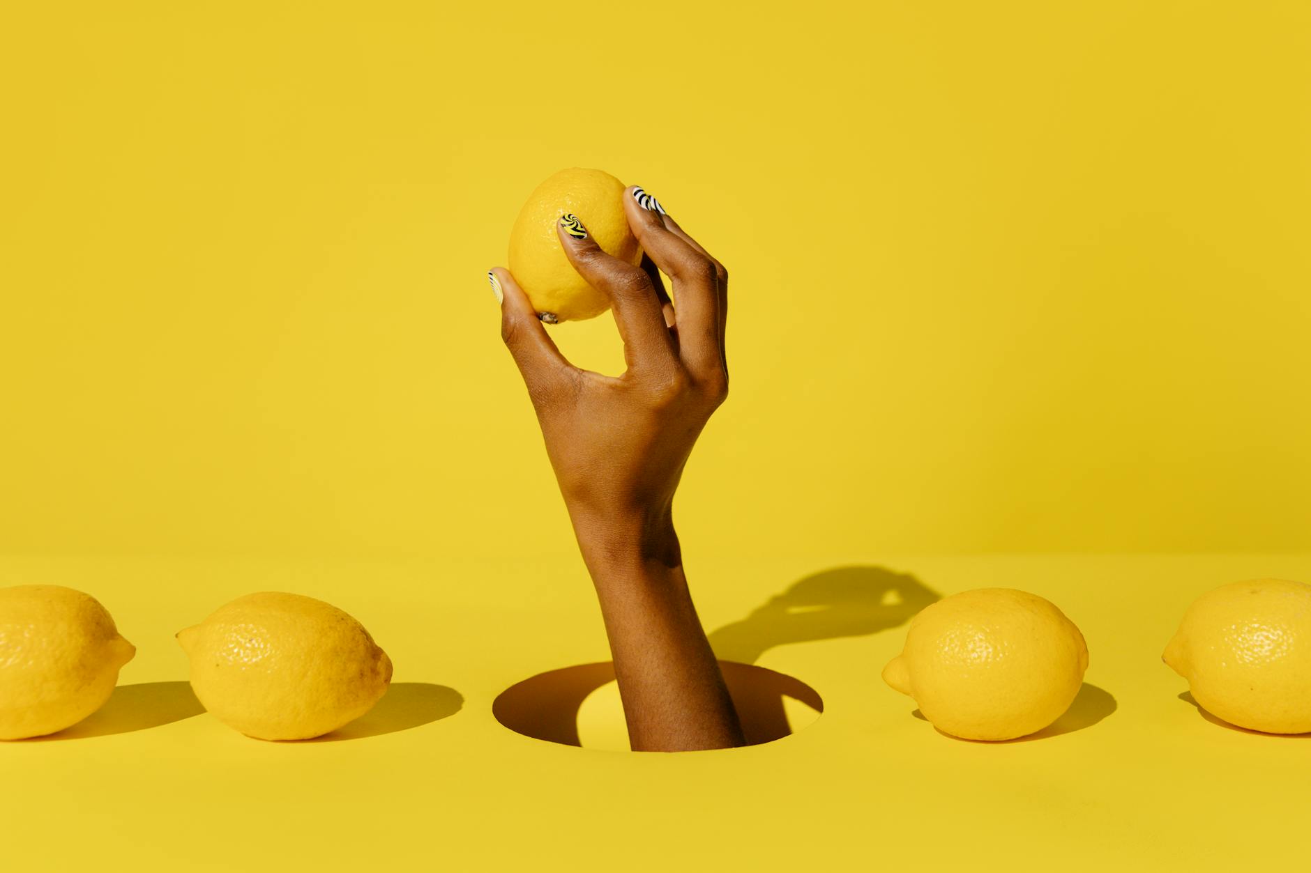 Hand holding a fresh lemon against a vivid yellow background, representing renewal and fresh connection