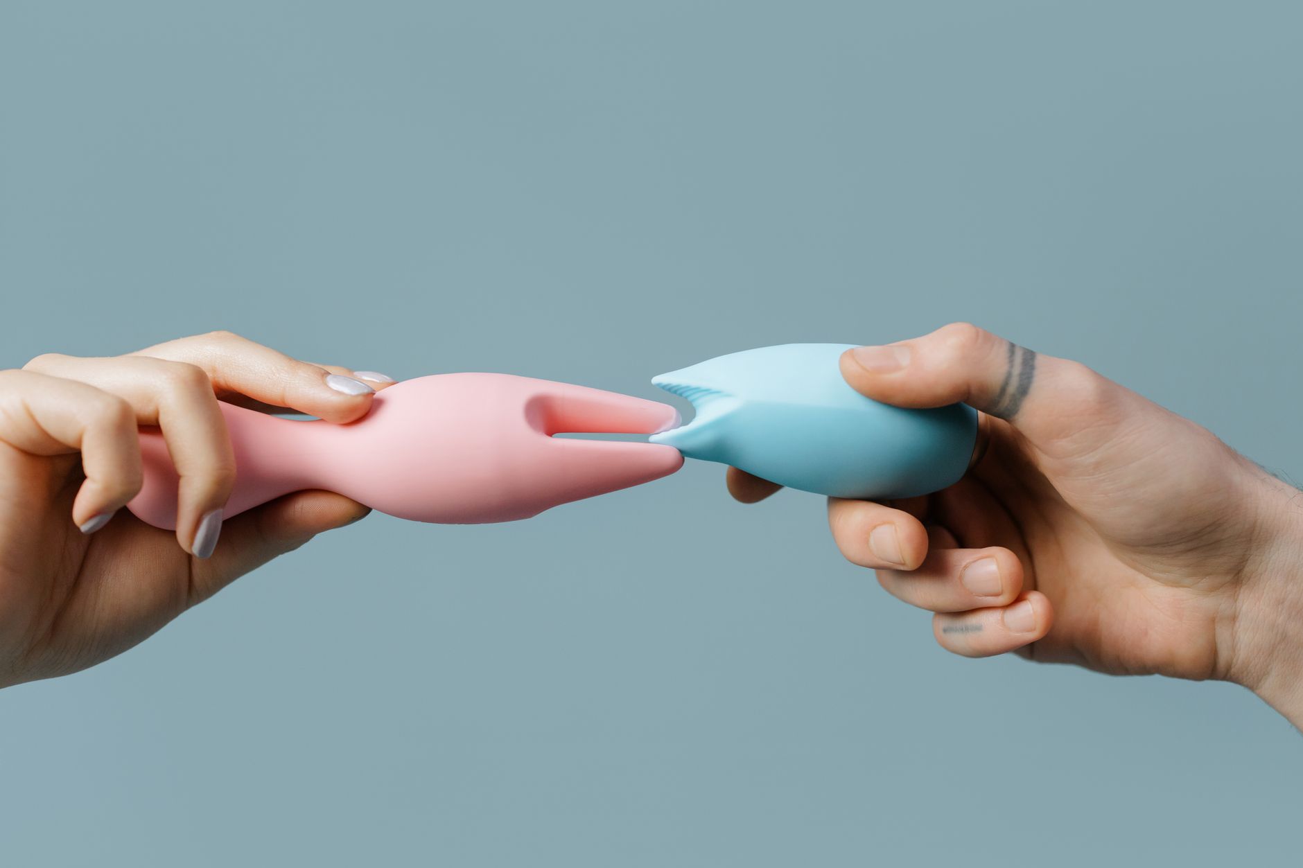 Mano sosteniendo un juguete de silicona rosa vibrante, mostrando productos para el placer sexual
