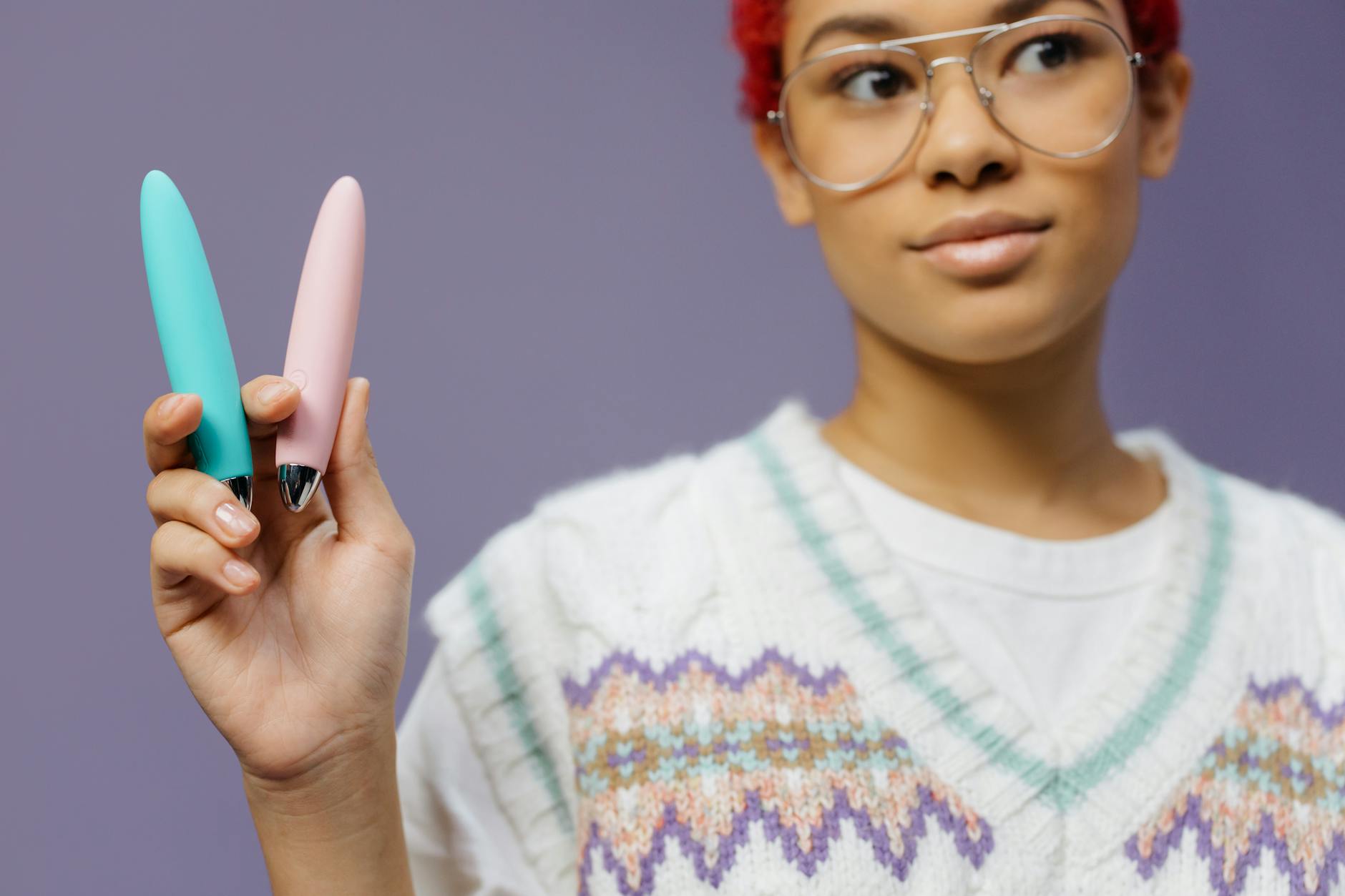 Woman holding colorful lemon vibrators and personal massagers against a purple background
