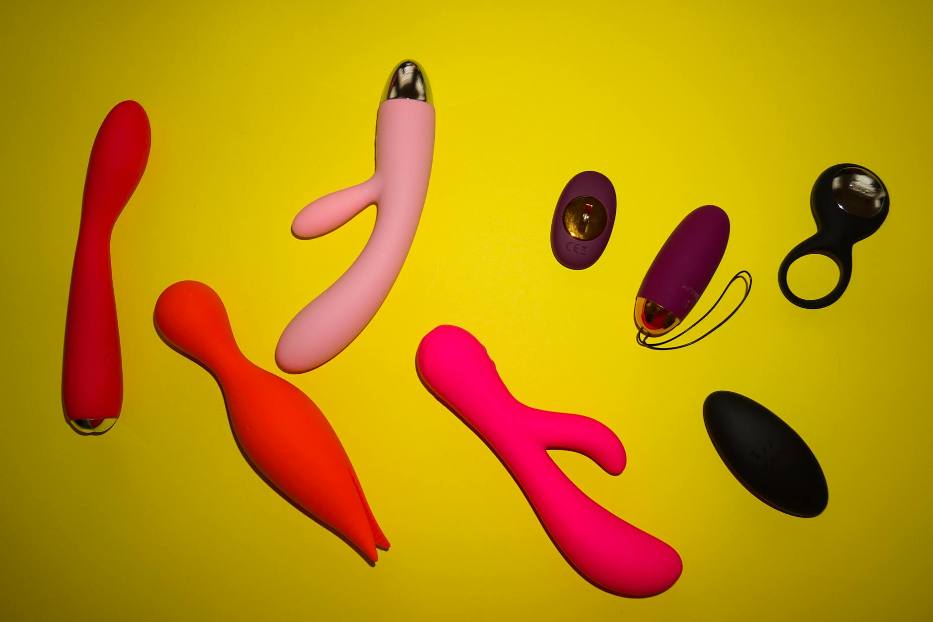 Vibrant arrangement of colorful adult toys on a bright yellow surface, showcasing different designs and textures