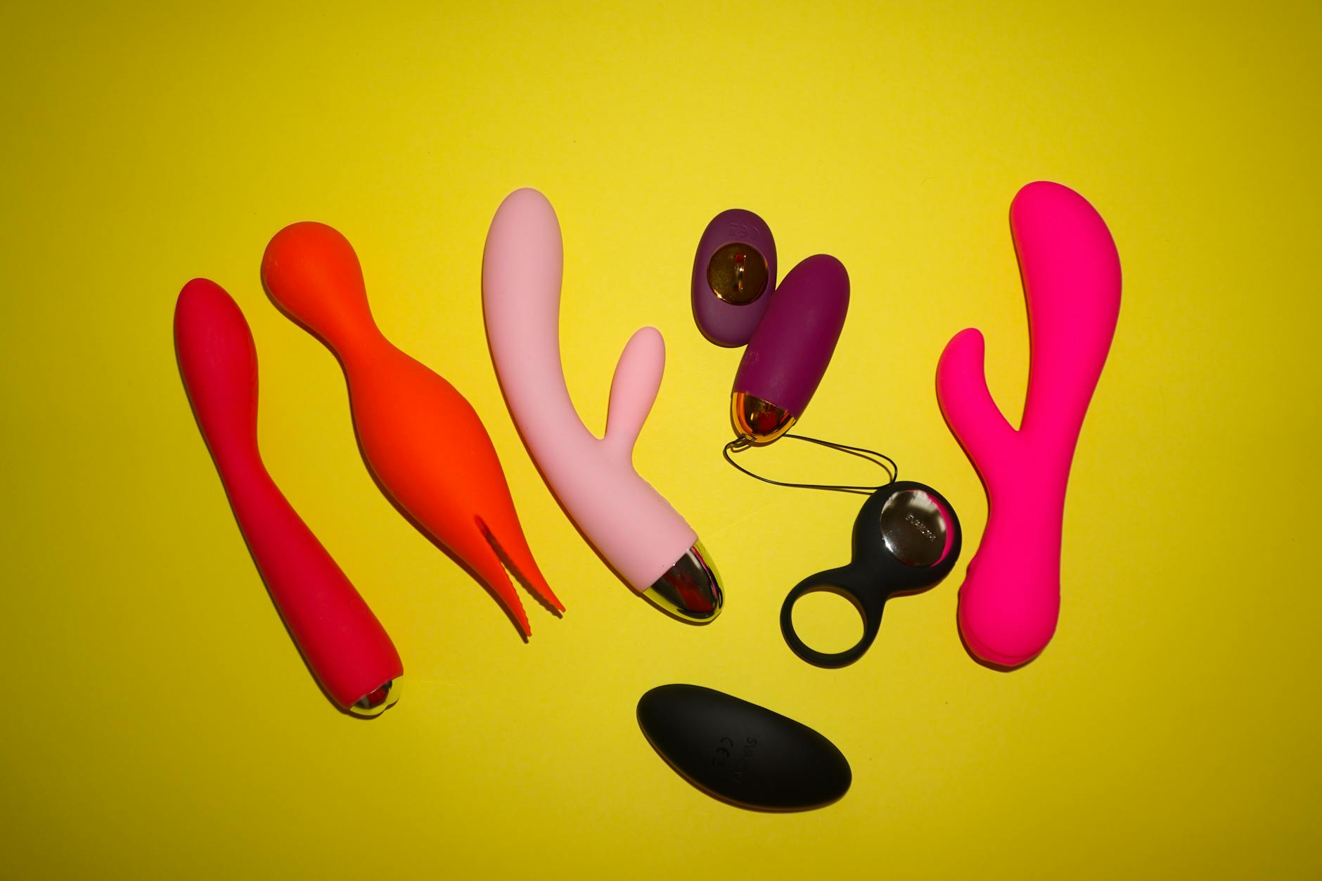 Collection of colorful vibrators and clitoral toys on a bright yellow background