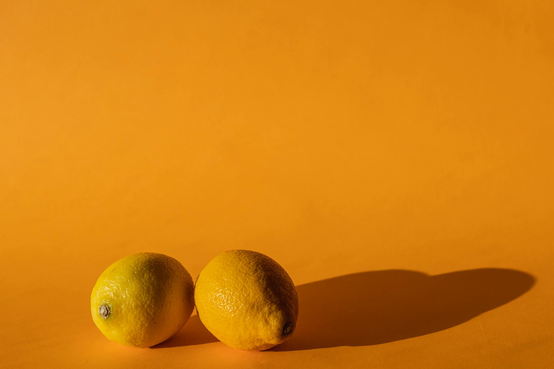 Ripe lemons on a yellow background symbolizing lemon clitoral vibrators and pleasure
